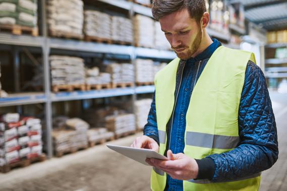 Ondernemer bekijkt in magazijn op zijn tablet het voorraadbeheerstysteem