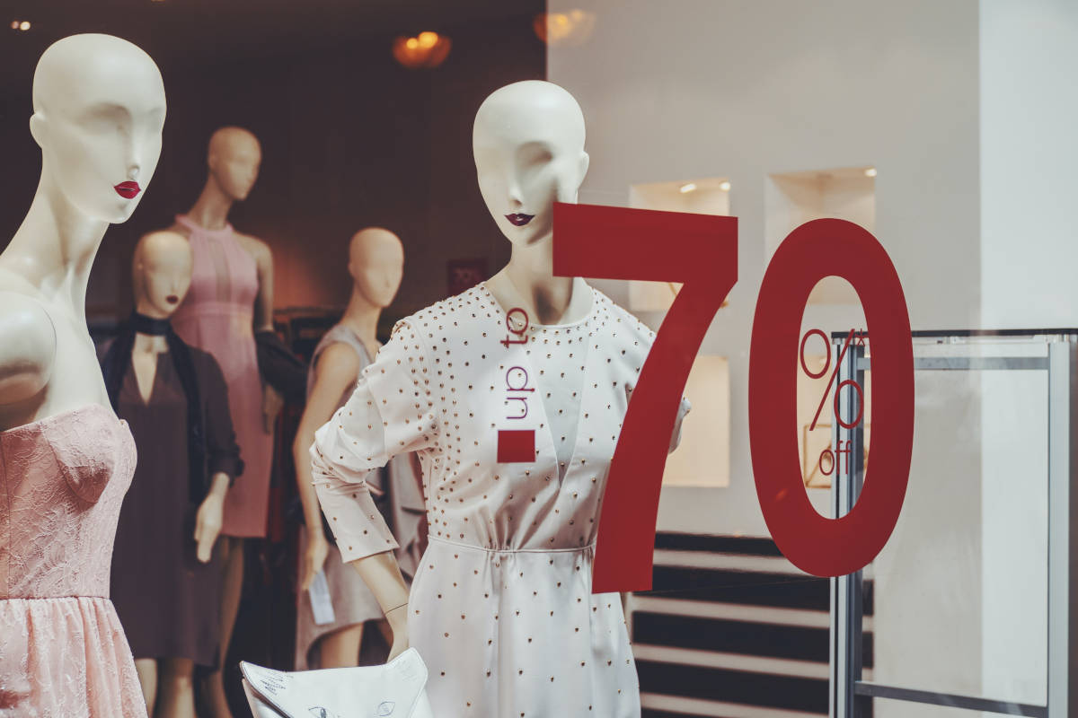 "Up to 70% off" op etalageruit met paspoppen erachter