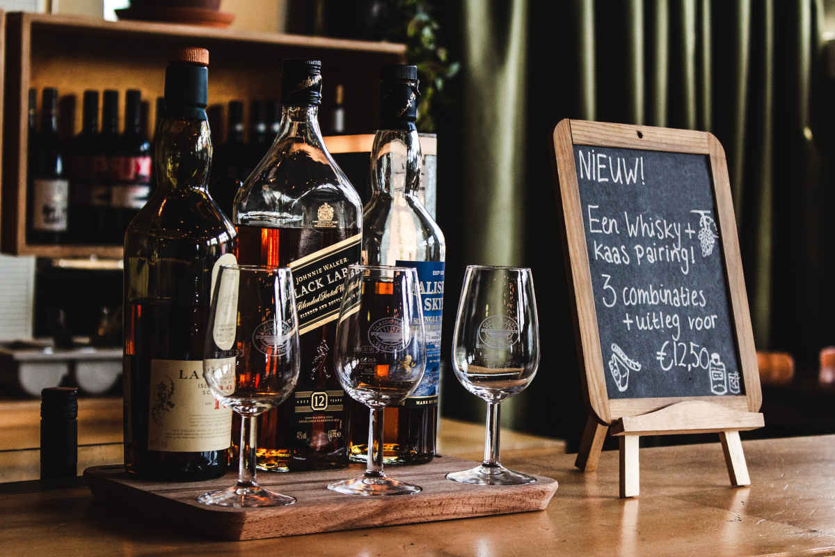 Plankje met sterke drank en bijbehorende glazen en een krijtbord met begeleidende tekst