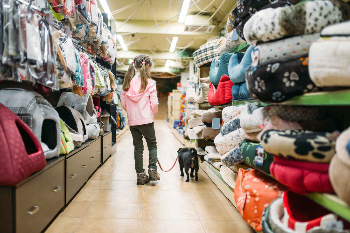 Meisje en hond lopen door gangpad in dierenwinkel