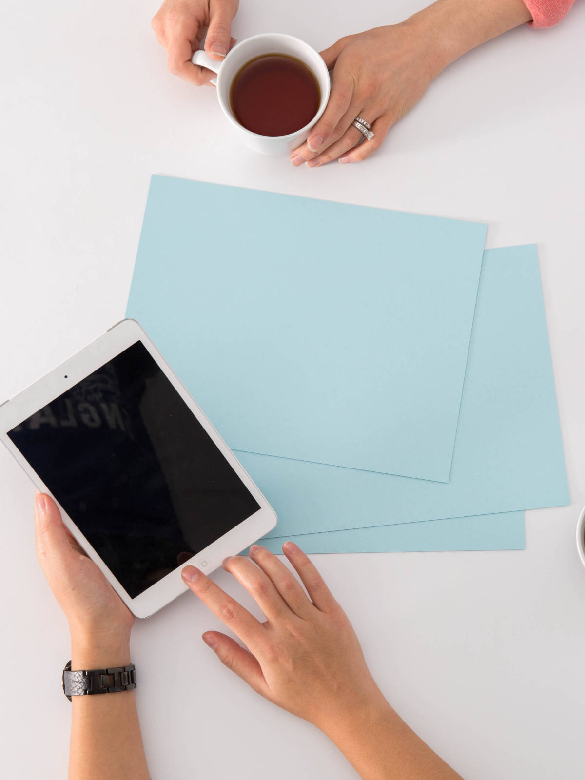 Overleg tussen twee personen met tablet, papieren en warme drank